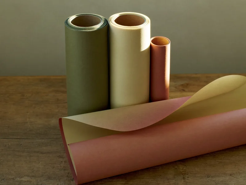 Rollen schlichten Geschenkpapiers in Terrakotta, Salbei und Creme, eine Rolle abgerollt